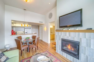 Una sala de estar moderna con chimenea, un comedor con sillas y una mesa, y una cocina al fondo.