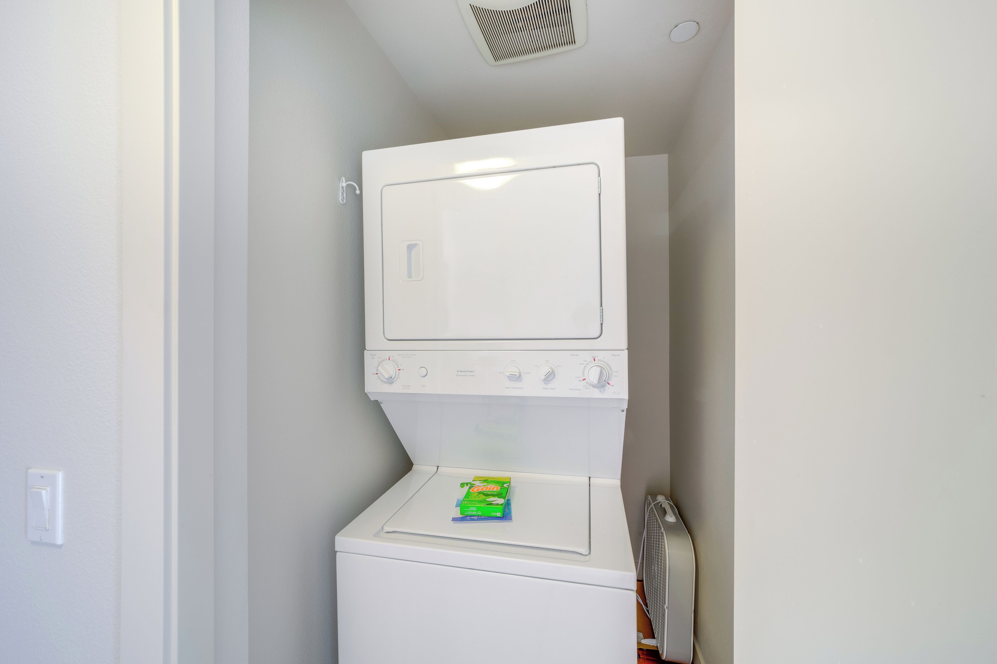 Una lavadora y secadora compactas en un lavadero pequeño, con un solo panel de control y una pequeña caja en la secadora.