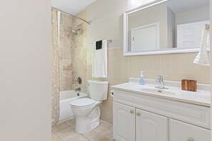 A bathroom with a shower, toilet, sink, and vanity.
