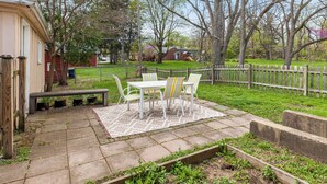 Eine Terrasse mit Tisch und Stühlen, einer hölzernen Bank und einem Blumenbeet mit Pflanzen.