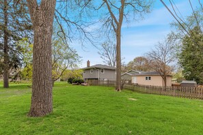 A residential area with a large tree, a wooden fence, and houses in the background.