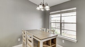 Un comedor con mesa y sillas de madera, una ventana con persianas y una lámpara.