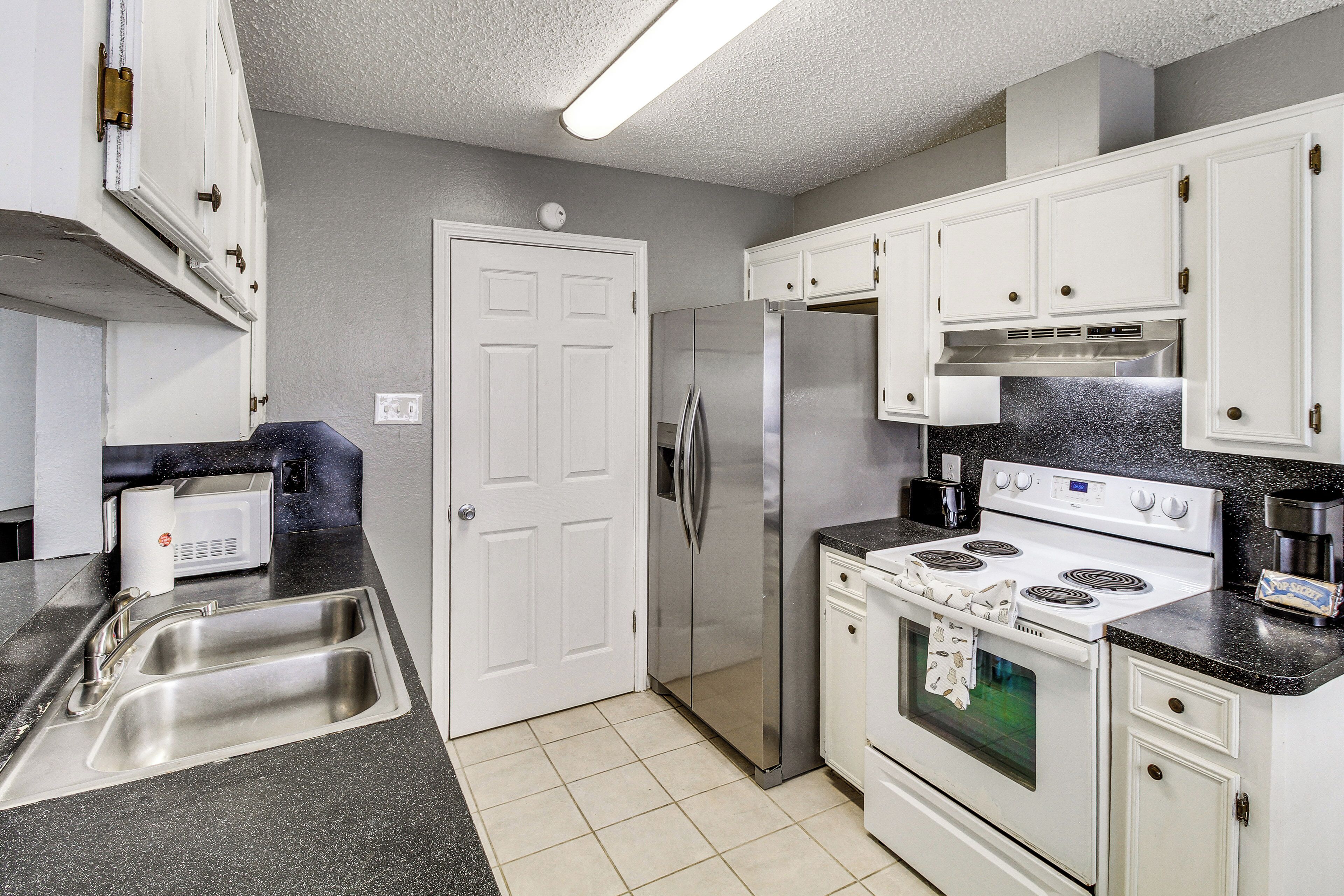 A kitchen with stainless steel appliances, a double sink, and white cabinetry.