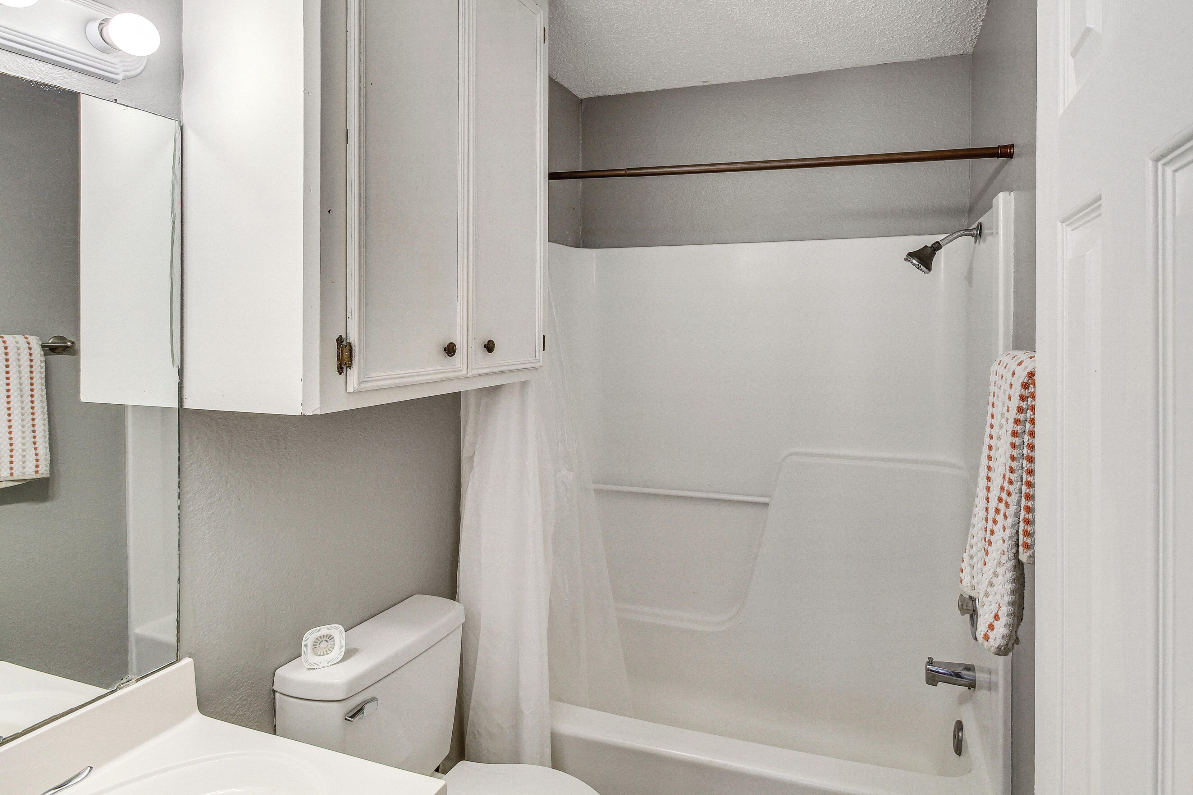 Ein Badezimmer mit Toilette, Waschbecken, Spiegel und Duschbereich.