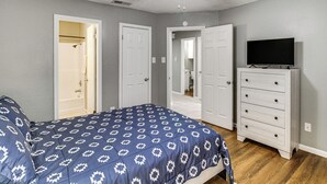 Un dormitorio con cama, ventilador de techo, cómoda y televisor.