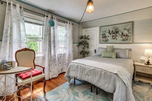 A bedroom with a bed, a chair, a table, a lamp, and a painting on the wall. - 'nanas Tiny Flat' East Side Charmer Near Brown (Providence)