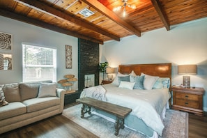 A bedroom with a bed, wooden headboard, bedside tables, a bench, a sofa, and a window with blinds. - 2 Mi to OKC Fairgrounds: Pet-friendly Home w/ Yard (Oklahoma City)