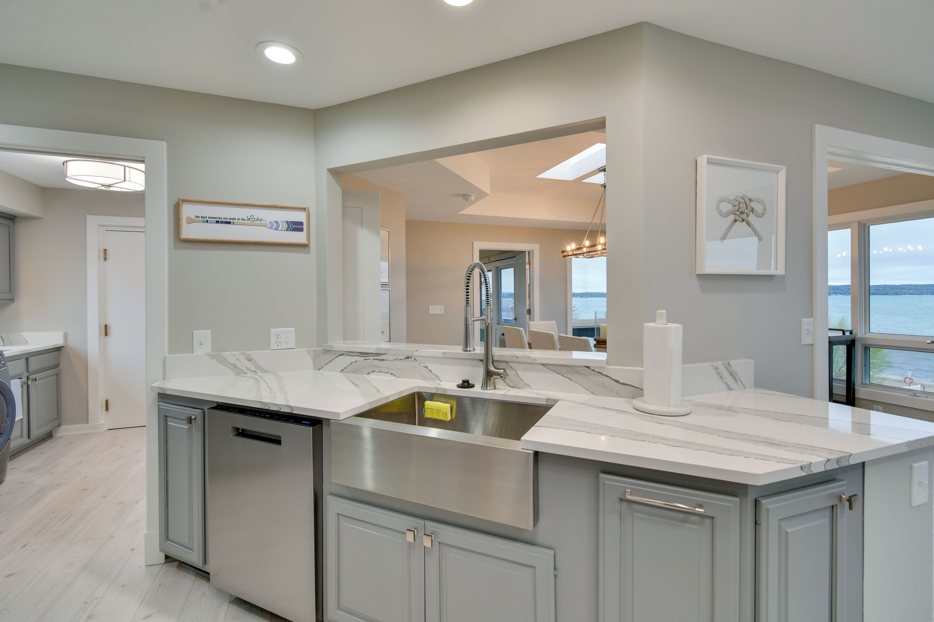 A modern kitchen with a large island, stainless steel appliances, and a view of the sea.