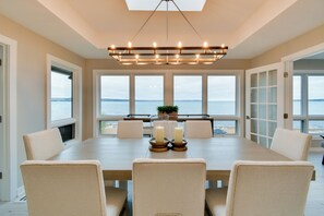 A dining area with a large table, chairs, candles, and a view of the sea. - Rooftop Deck, Bay Views! Traverse City Penthouse (Traverse City)