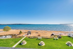 A beach view with a gazebo, lounge chairs, and a grassy area with tables. - Rooftop Deck, Bay Views! Traverse City Penthouse (Traverse City)