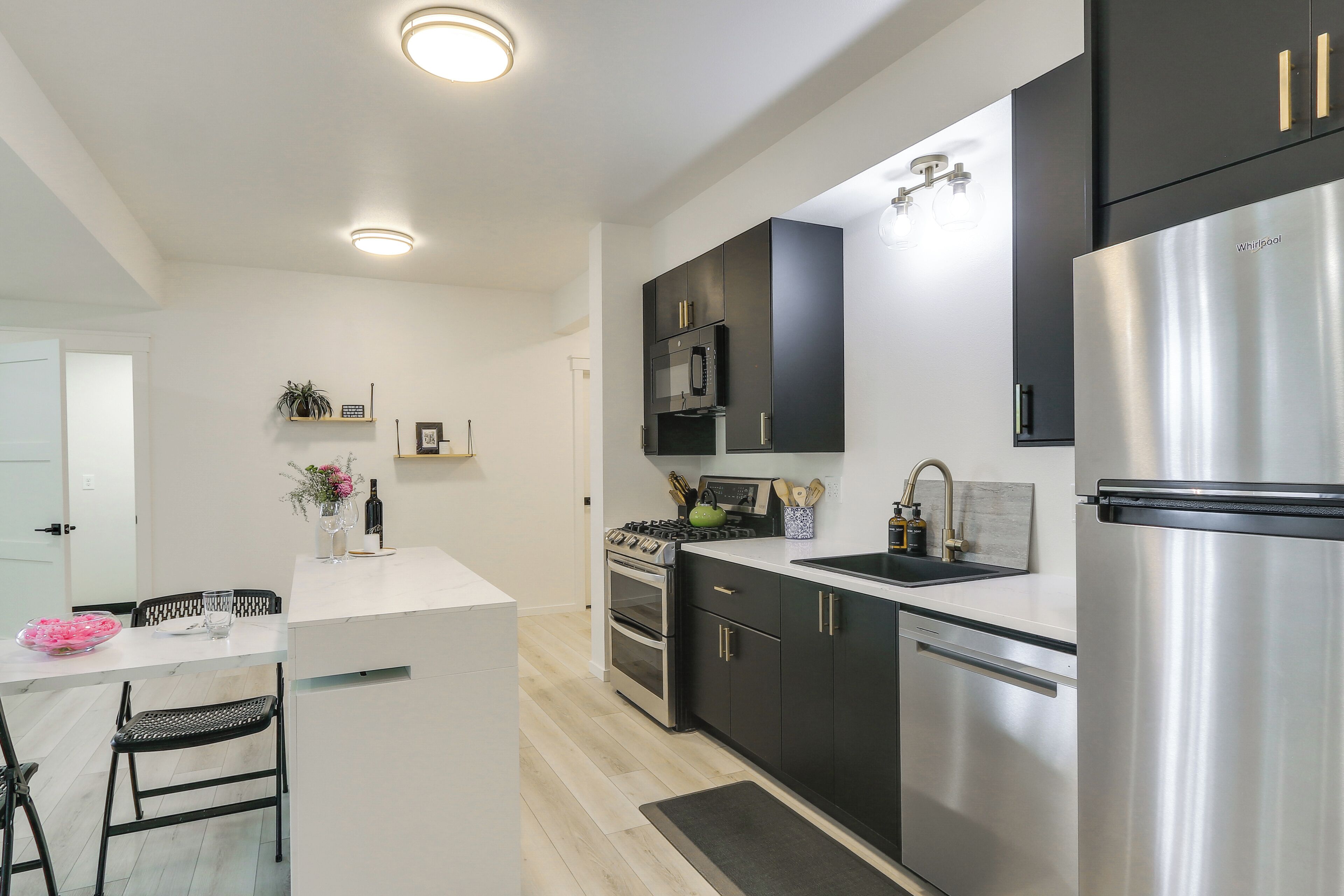 A modern kitchen with a central island, stainless steel appliances, and black cabinetry.