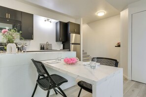 A modern kitchen with a marble island, black chairs, and a stainless steel refrigerator. - Front Range, Rocky Mtn Nat'l Park Base: Golf Views (Loveland)