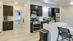 Una cocina moderna con armarios oscuros, electrodomésticos de acero inoxidable y una isla central con asientos.