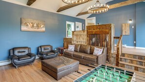 Ein Wohnzimmer mit Ledersofas, einem Kicker und einer Holzkommode.