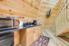 Un interior de madera con una zona de cocina que incluye microondas, cafetera y lavamanos.
