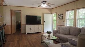 A living room with a flat-screen TV, wooden cabinets, a sofa, and a ceiling fan. - Lakeview Legacy~Holmes Bend Marina~Walk to Lake (Columbia)