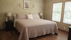 Un dormitorio con una cama grande, dos mesitas de noche y una ventana con persianas.