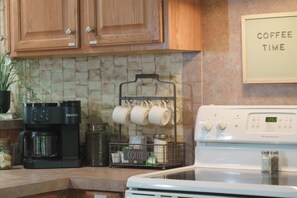 A kitchen with a coffee maker, a kettle, a coffee mug rack, and a stove. - Lakeview Legacy~Holmes Bend Marina~Walk to Lake (Columbia)