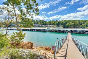 A pier leading to a dock with a caution sign, a body of water, and a forested hillside in the background. - Spacious Lake Norris Getaway w/ Resort Perks! (La Follette)