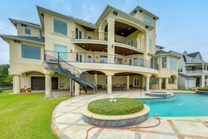 A multi-story house with a swimming pool, outdoor seating, and a covered patio area.