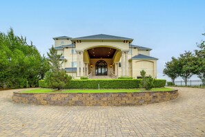 A large, two-story building with a symmetrical facade, a central entrance with a portico, and a landscaped front yard. - Bayfront Villa w/ Million-dollar Views in Seabrook (Seabrook)
