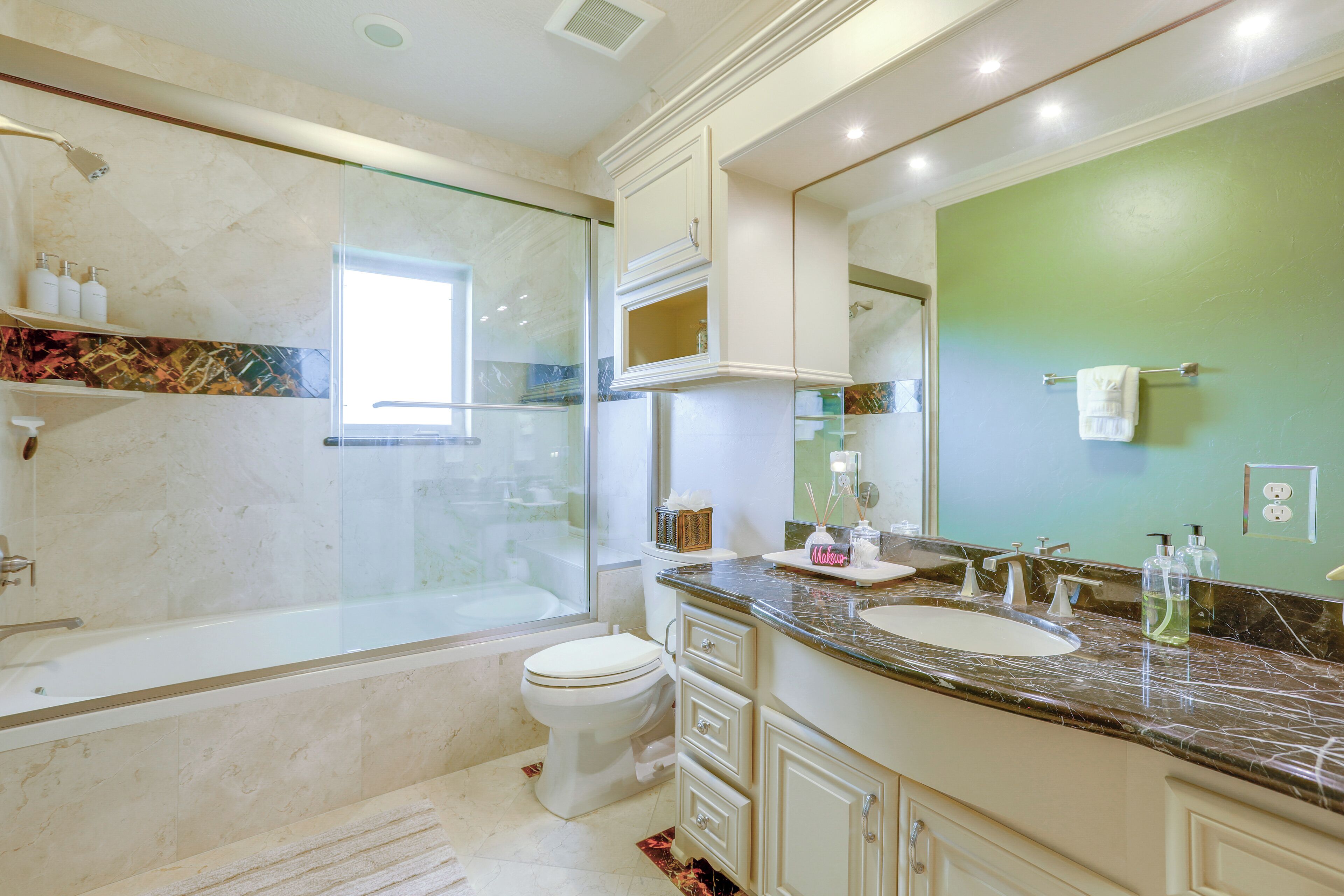 Une salle de bain avec une baignoire, des toilettes, un meuble-lavabo et un grand miroir.