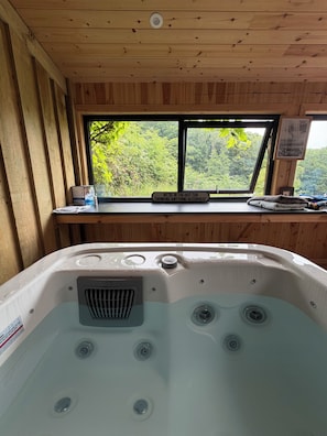 Ein Whirlpool mit Blick durch ein Fenster auf einen Wald.