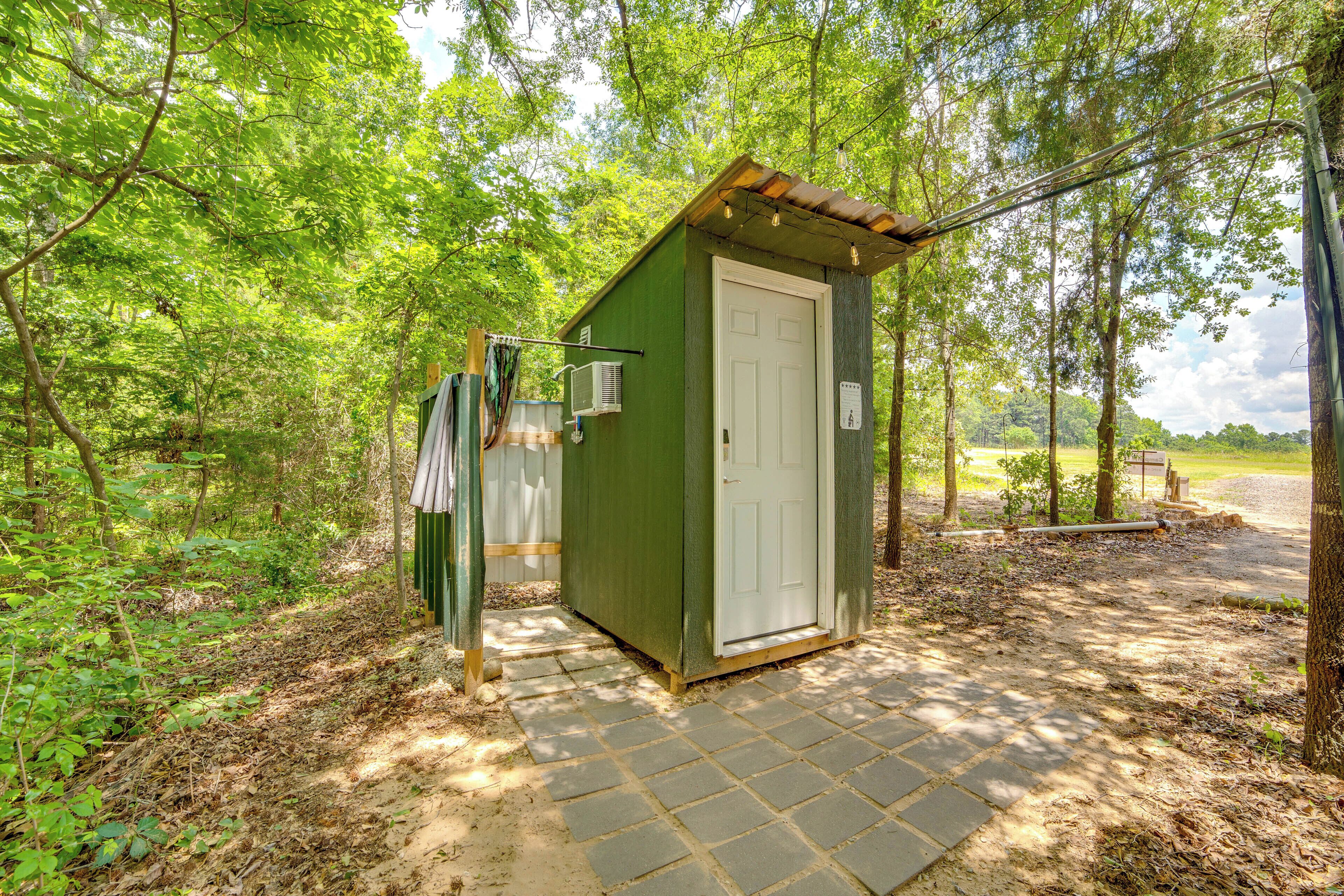 Une petite construction en bois, de couleur verte, dotée d’une porte, d’une fenêtre et d’un petit espace en forme de porche.