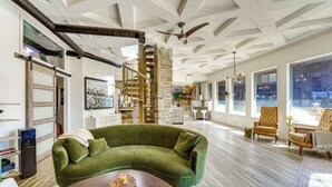 Un salón espacioso con un sofá verde, una mesa de centro de madera y una escalera en espiral.