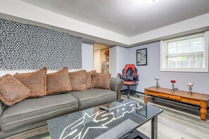 A living room with a sofa, a coffee table, a gaming chair, and a wooden side table. - Near Southern Regional MC! Commuter-friendly Base (Riverdale)