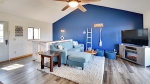 A living room with a blue accent wall, a ceiling fan, a TV, and a fireplace. - 3-unit Combo w/ Dock on Lake Keowee - Hike & Fish! (Seneca)