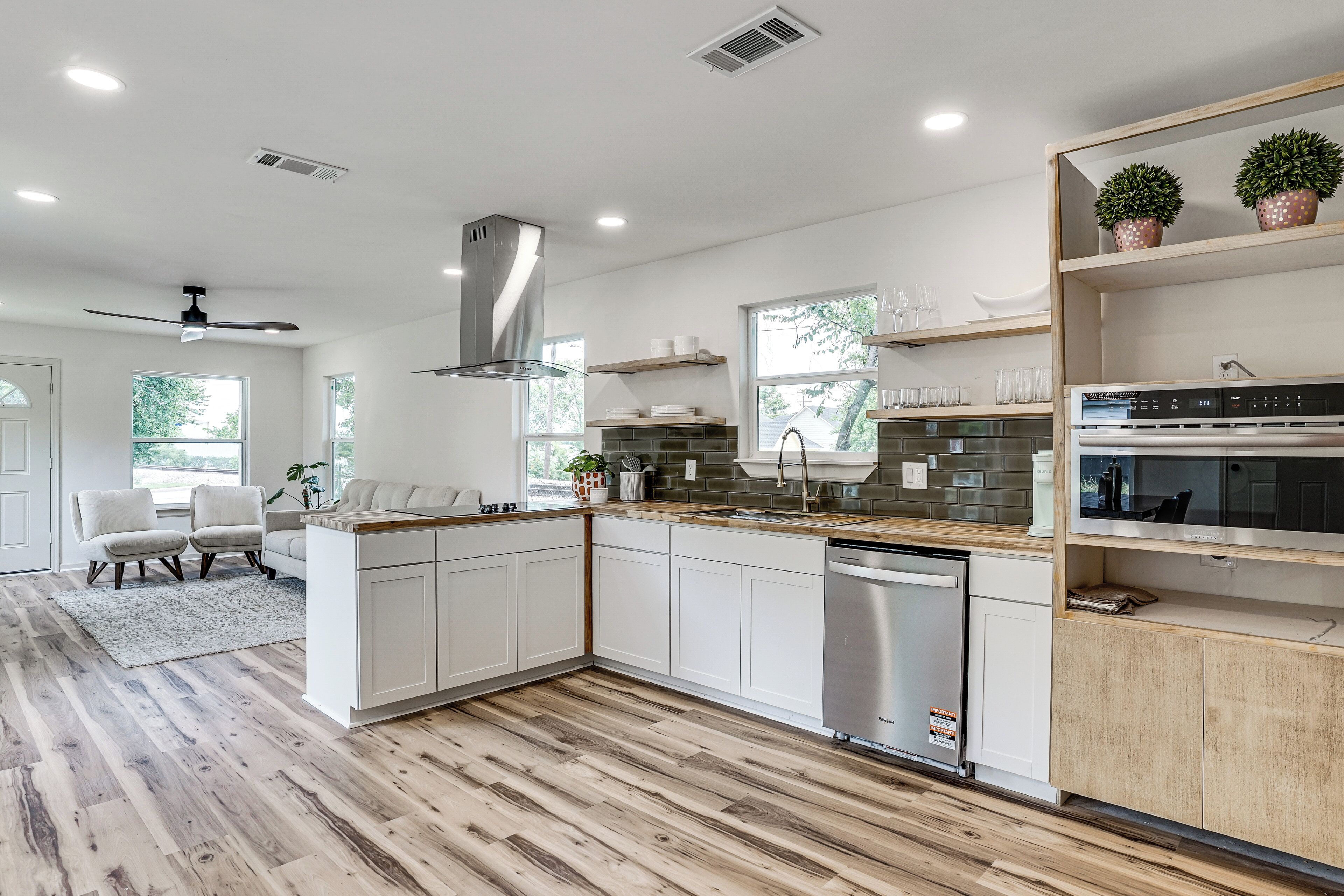 Una cocina moderna con armarios blancos, lavavajillas de acero inoxidable y encimera de madera.