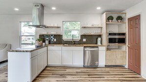 A modern kitchen with white cabinets, a stainless steel dishwasher, and a wooden countertop. - Updated Craftsman in Historic Southside Fort Worth (Fort Worth)