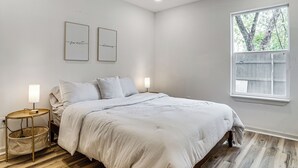 A bedroom with a bed, bedside tables, a ceiling fan, a window, and two wall art pieces. - Updated Craftsman in Historic Southside Fort Worth (Fort Worth)