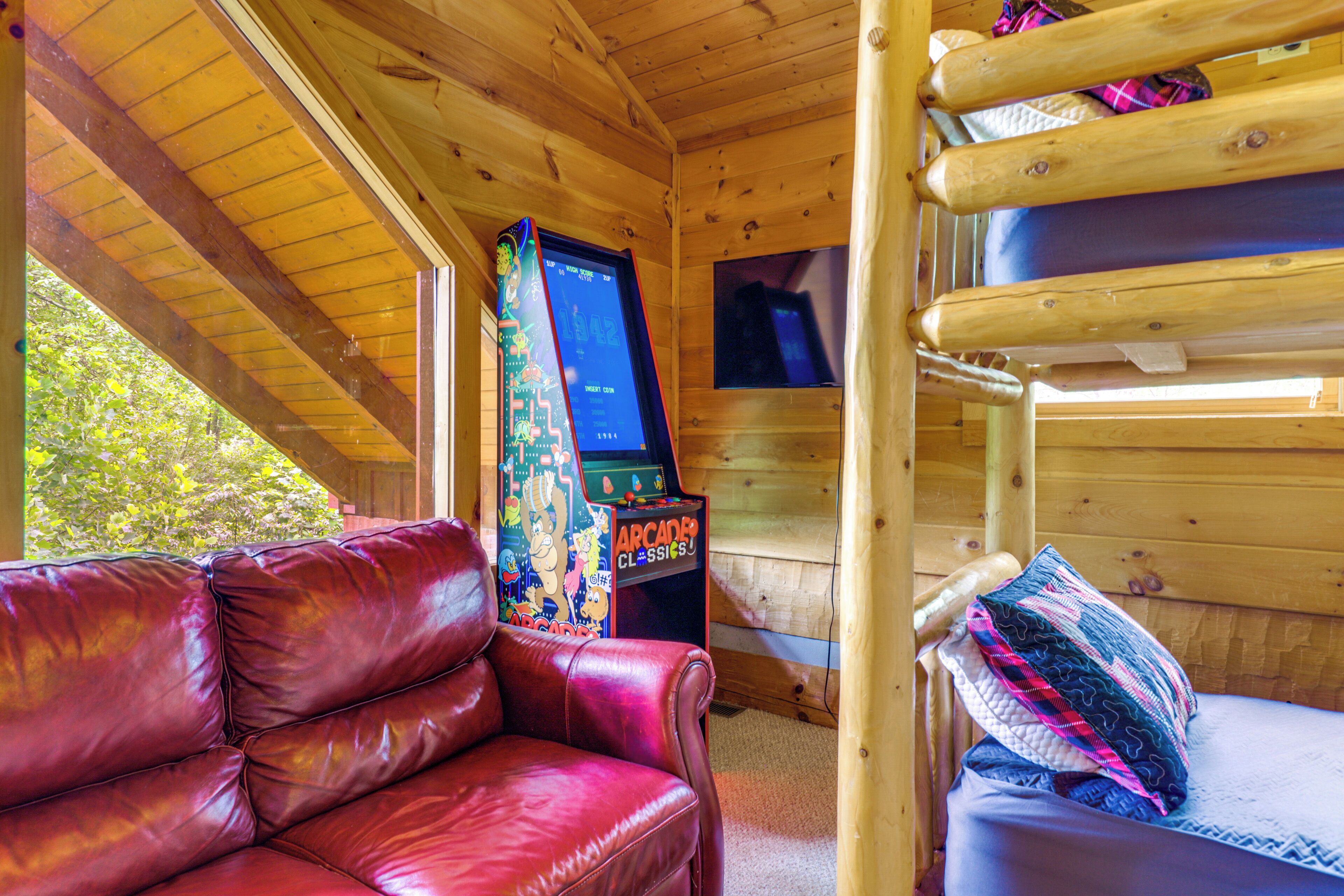 A wooden cabin interior with a red leather couch, bunk beds, and a video game console.