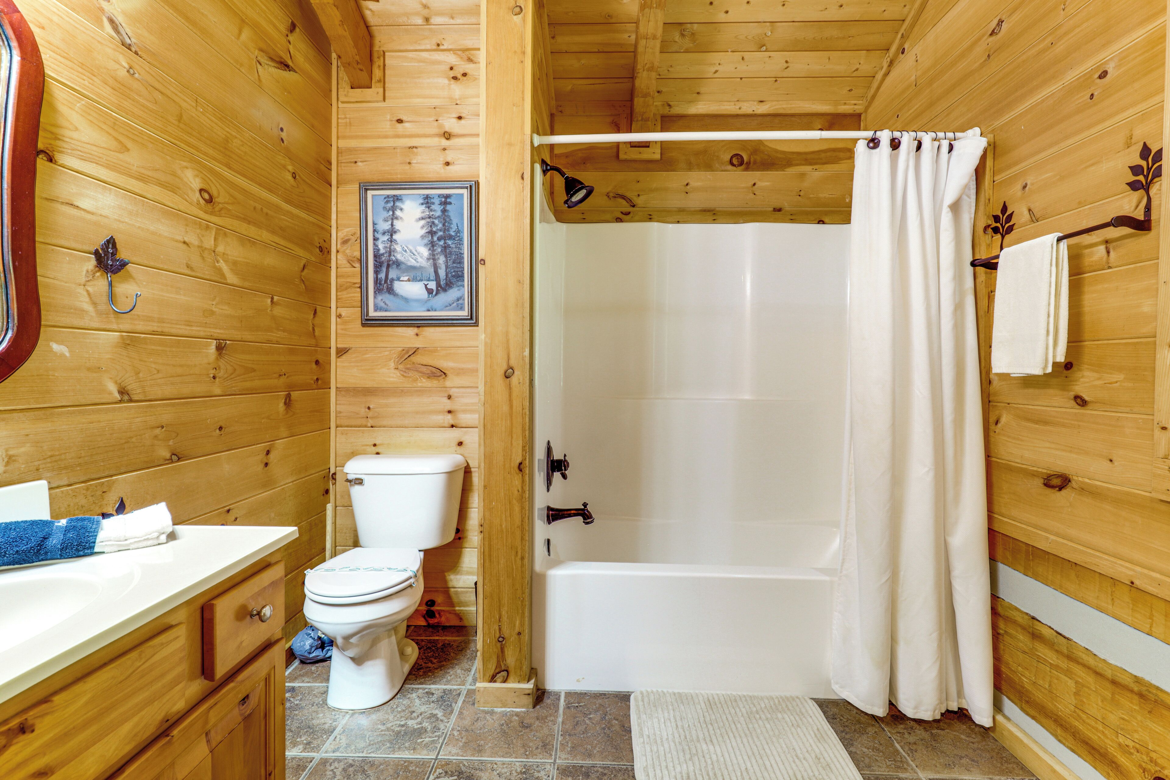 A wooden cabin bathroom with a toilet, sink, and bathtub.