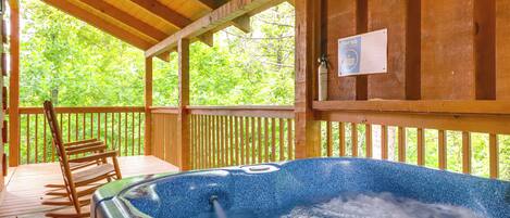 Une terrasse en bois avec un jacuzzi, des rampes en bois et une chaise.