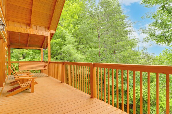 Eine Holzterrasse mit Geländer, einer Bank und Stühlen.