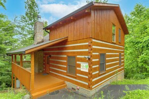 Eine Blockhütte mit Veranda, Schornstein und einem Schild, das darauf hinweist, dass es sich um eine Ferienunterkunft handelt.