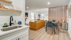 Een moderne keuken met een spoelbak, houten planken en een zithoek met een bank en stoelen.