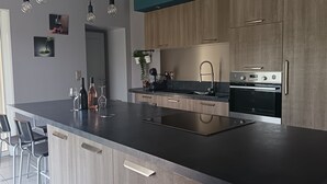 Una cucina moderna con isola centrale, elettrodomestici in acciaio inossidabile e illuminazione a sospensione.