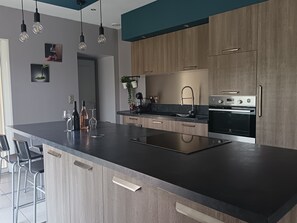 A modern kitchen with a central island, stainless steel appliances, and pendant lighting. - House in the heart of a vineyard in Provence at the foot of Mont Ventoux (Carpentras)