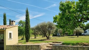 Una casa con un muro in pietra, un albero e cielo sereno.