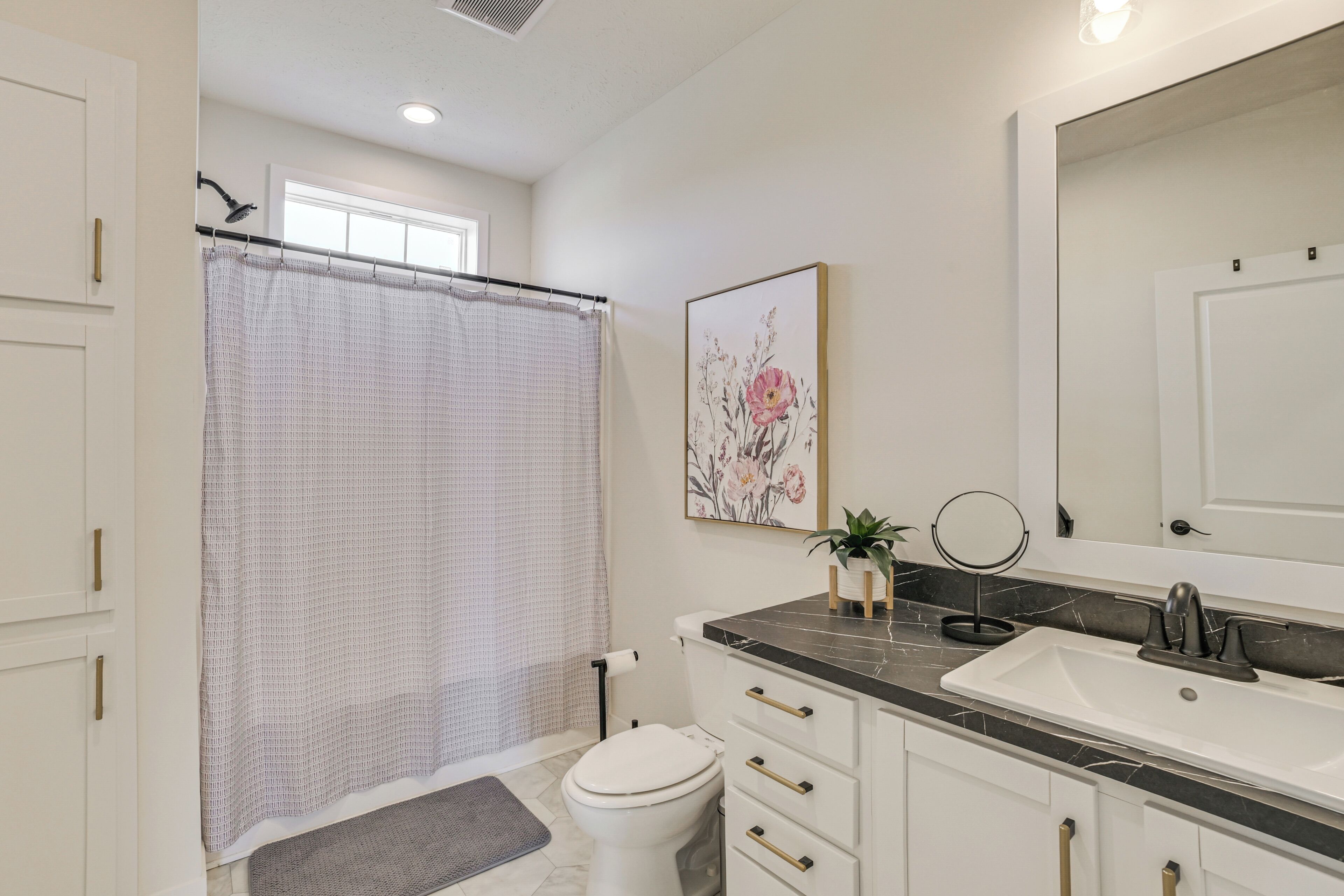 Une salle de bain équipée d’un rideau de douche, de toilettes, d’un lavabo et d’un miroir.