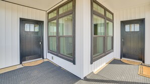 Canto de um quarto com duas portas, janelas grandes e um tapete de entrada estampado.