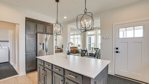 Uma cozinha moderna com uma ilha grande, eletrodomésticos de aço inoxidável e iluminação pendente.