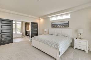 Um quarto com uma cama grande, uma mesa de cabeceira, uma janela e uma porta.