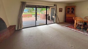 A room with a sliding glass door leading to an outdoor patio, a wooden cabinet, and a dining table with chairs. - Mountain View! 55-plus Green Valley Townhome (Green Valley)