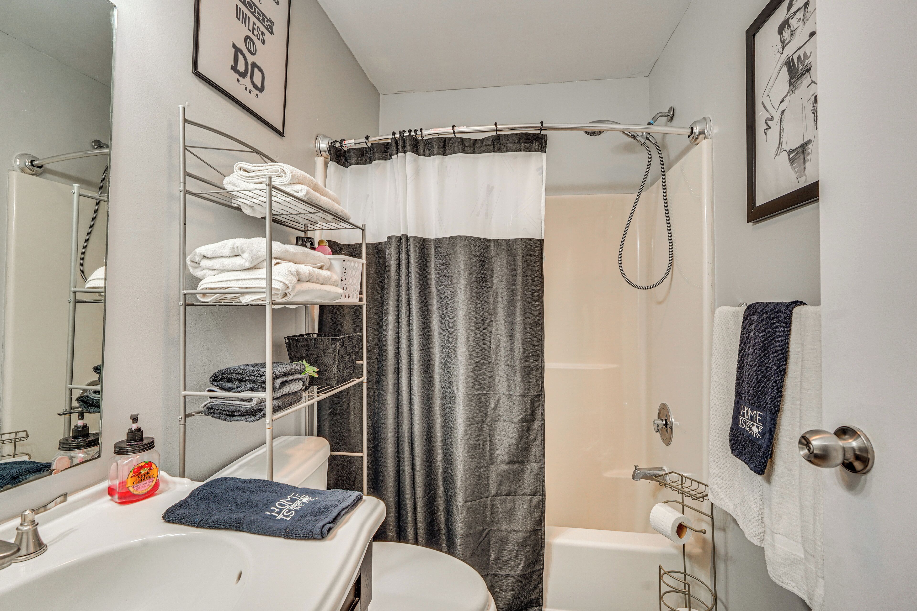A bathroom with a white sink, a toilet, a shower with a curtain, and a towel rack with towels.