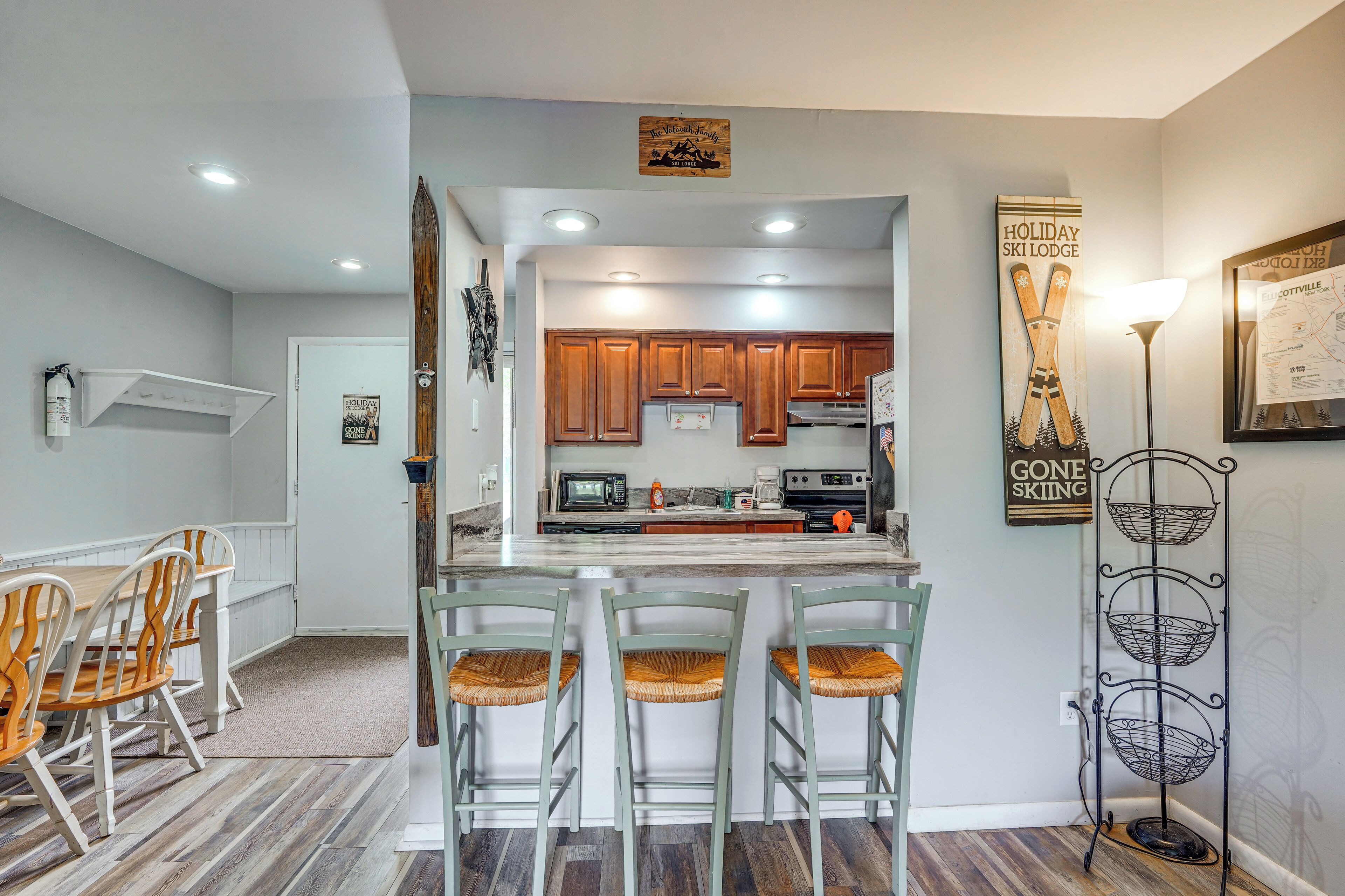 Una cocina con armarios de madera, una isla central y una zona de comedor con sillas de madera.